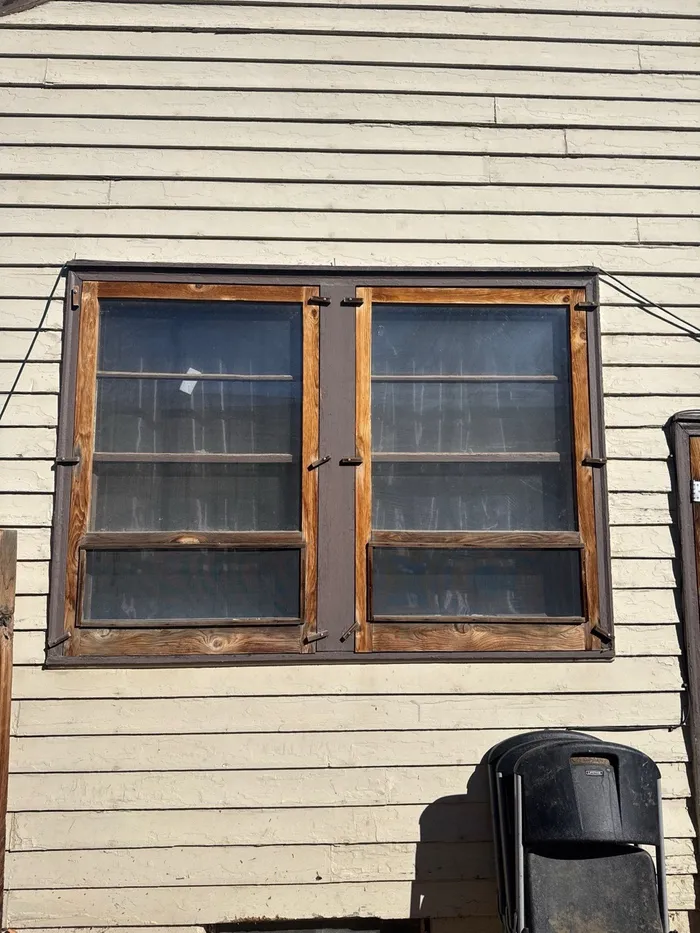 Original wood-frame window with peeling paint on an Englewood home, before replacement